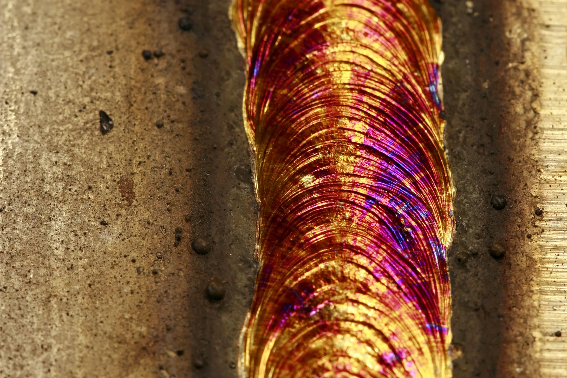 Close-up van een lasnaad in inox met goudkleurige en paarse verkleuring