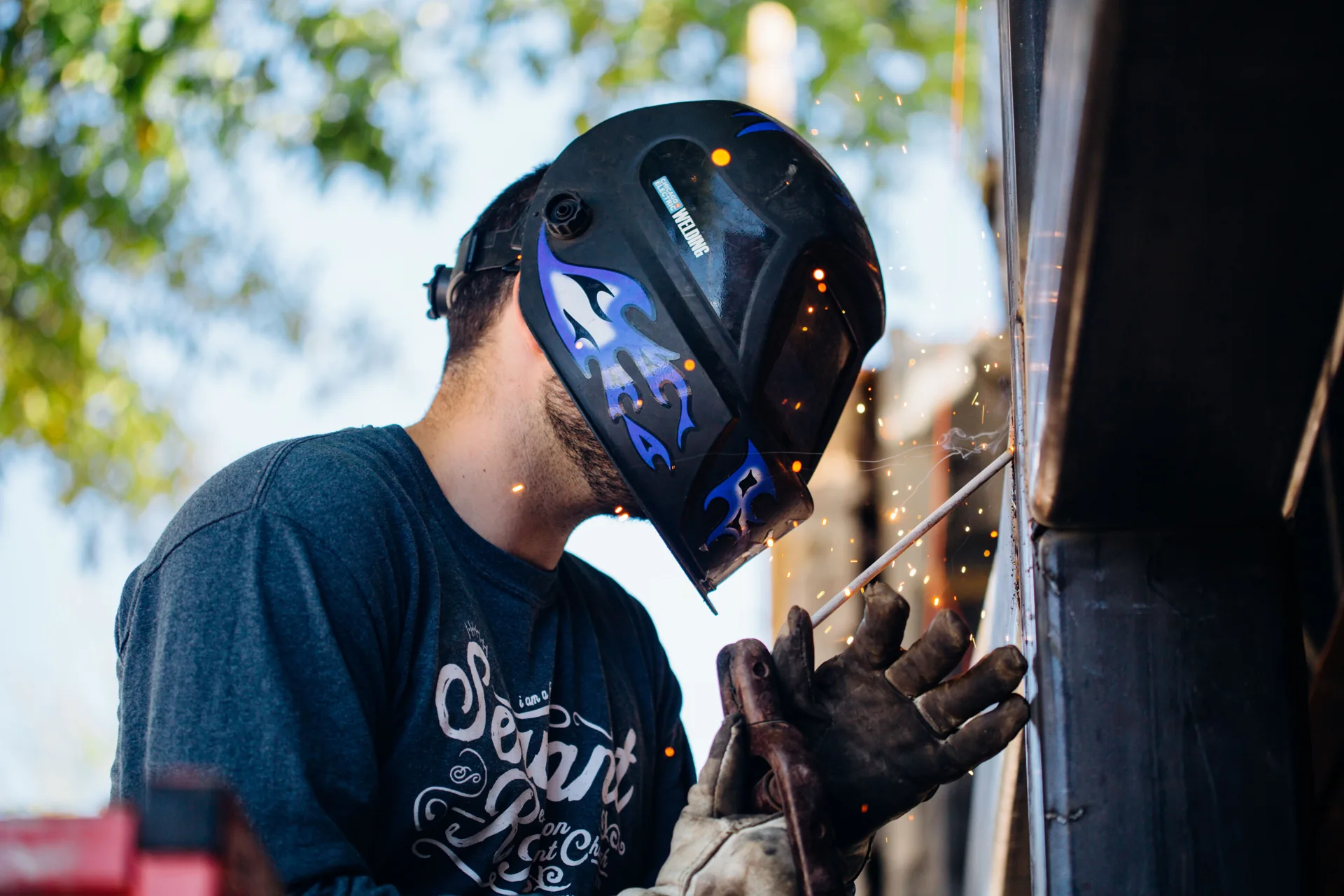 Lasser werkt met helm en handschoenen aan een verticale metaalverbinding